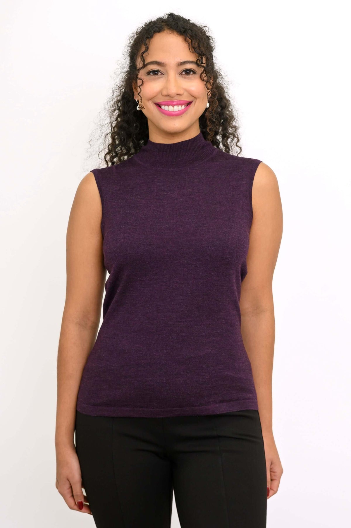 Smiling woman facing forward in a sleeveless purple mock neck sweater