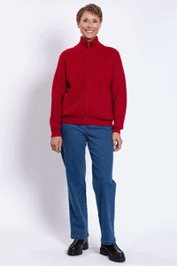 Person smiling, wearing a red ribbed cardigan sweater and blue jeans