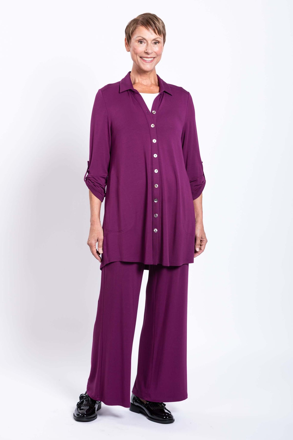 Front view of smiling model in plum tunic with rolled sleeves and matching pants
