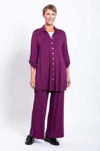 Front view of smiling model in plum tunic with rolled sleeves and matching pants