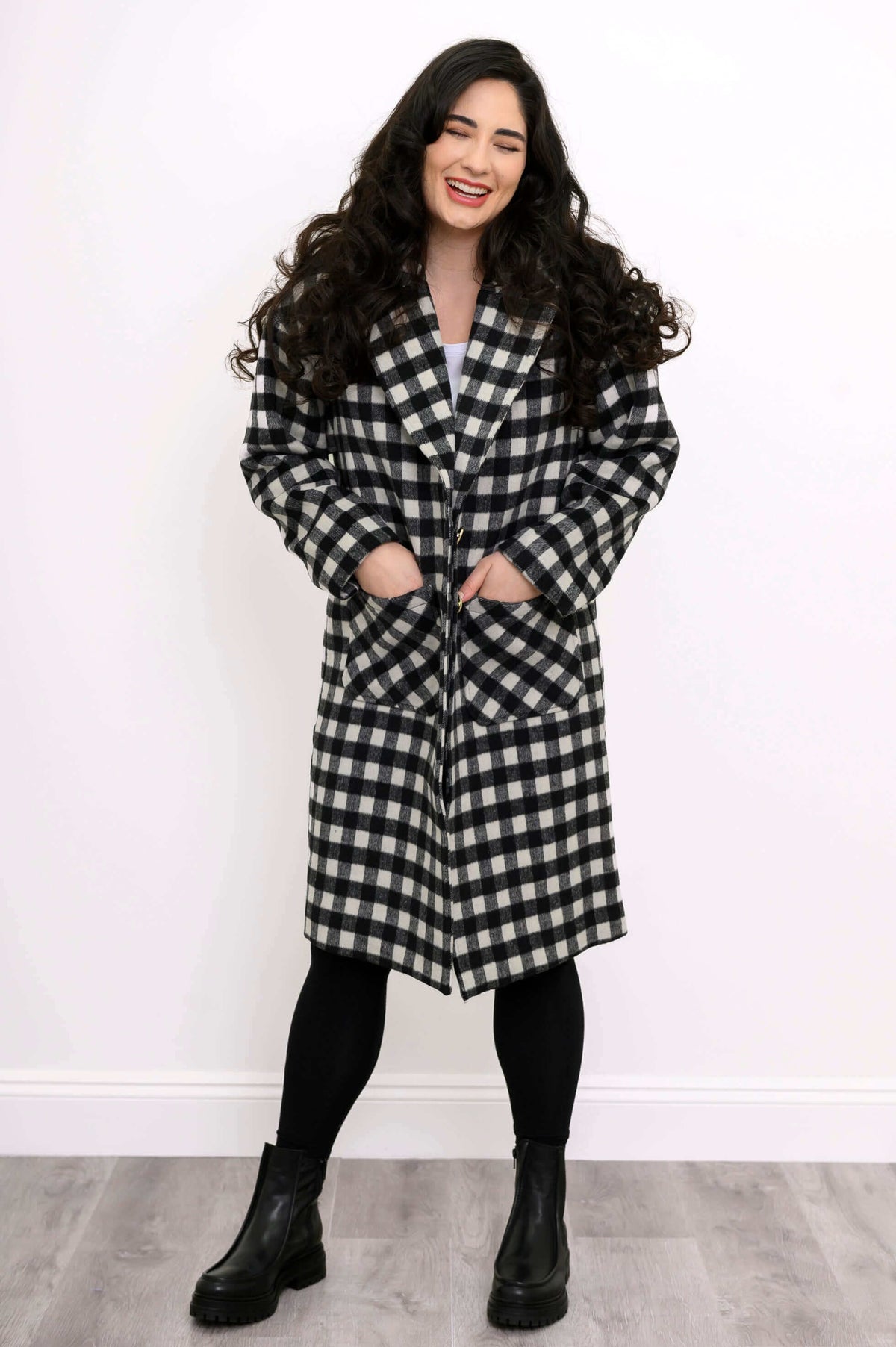 Model smiling in front view, black and white checkered coat, patch pockets, button closure