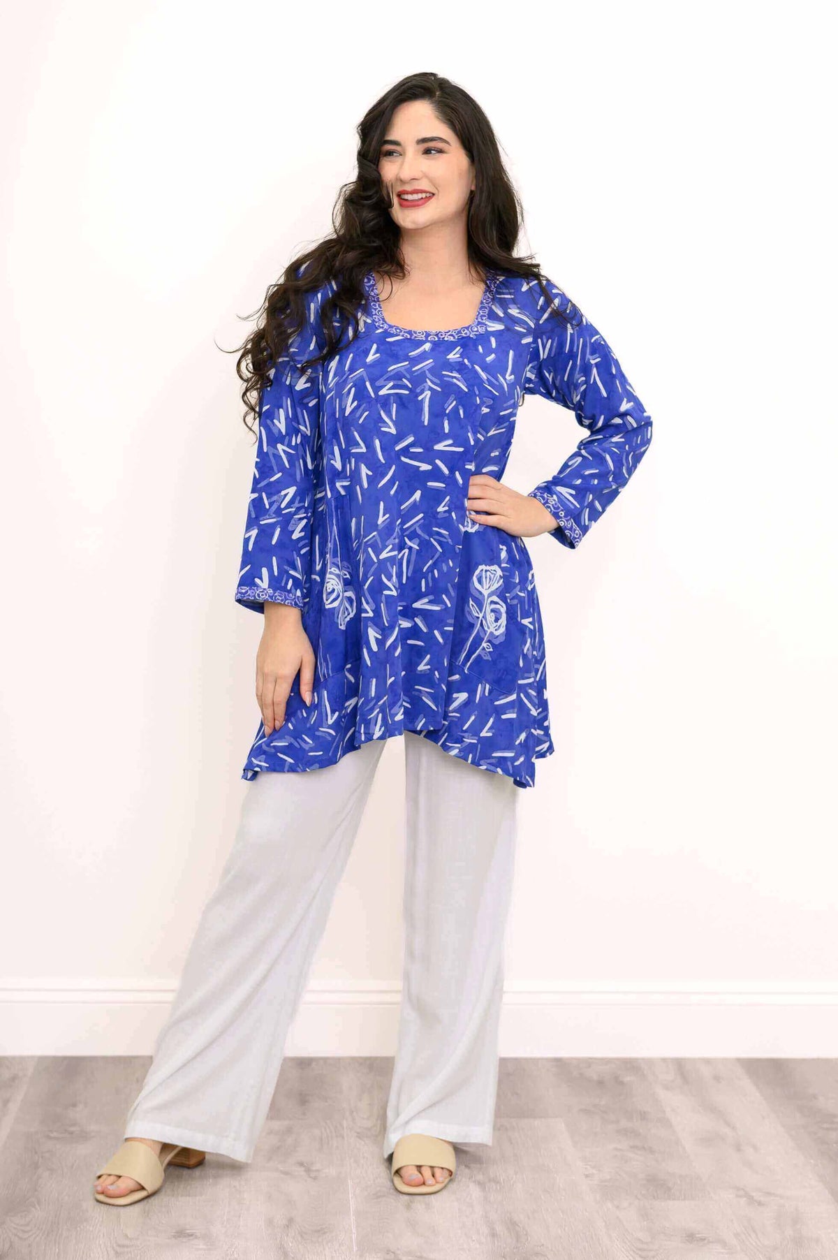 Smiling model in a blue tunic top with patch pockets and white pants