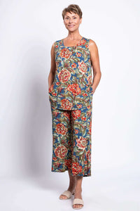 Woman smiling and posing in peony print sleeveless tank top and loose pants, hands in pockets
