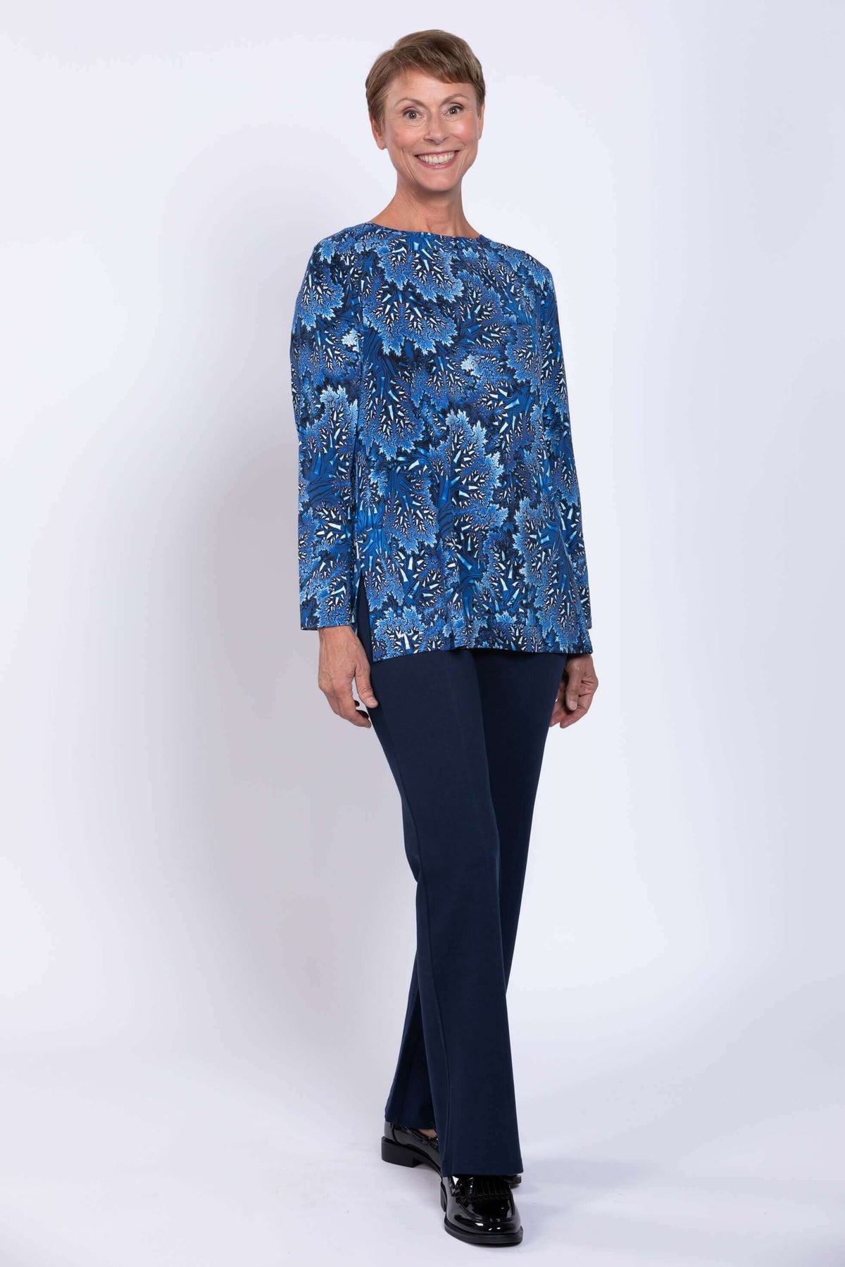 Smiling woman wearing a blue botanical print top and navy pants