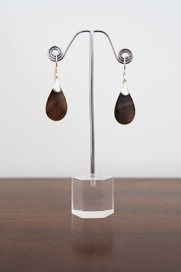 Front view of a pair of sterling silver and brown stone earrings displayed on a clear stand and white background, front view