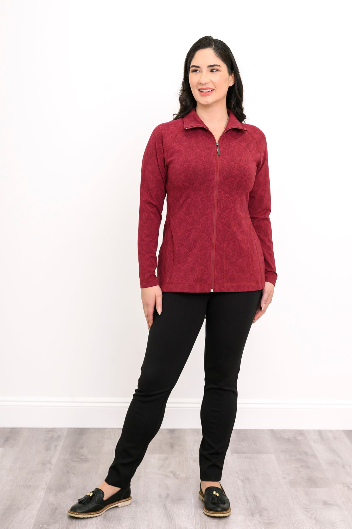 Front view of a women's red geometric print athletic jacket with pockets and a high collar, paired with black pants.