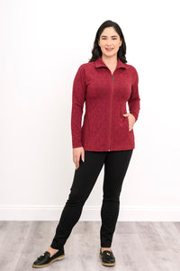 Smiling woman posing in a red patterned bamboo zip-up jacket with her hand on her hip, front-facing view.