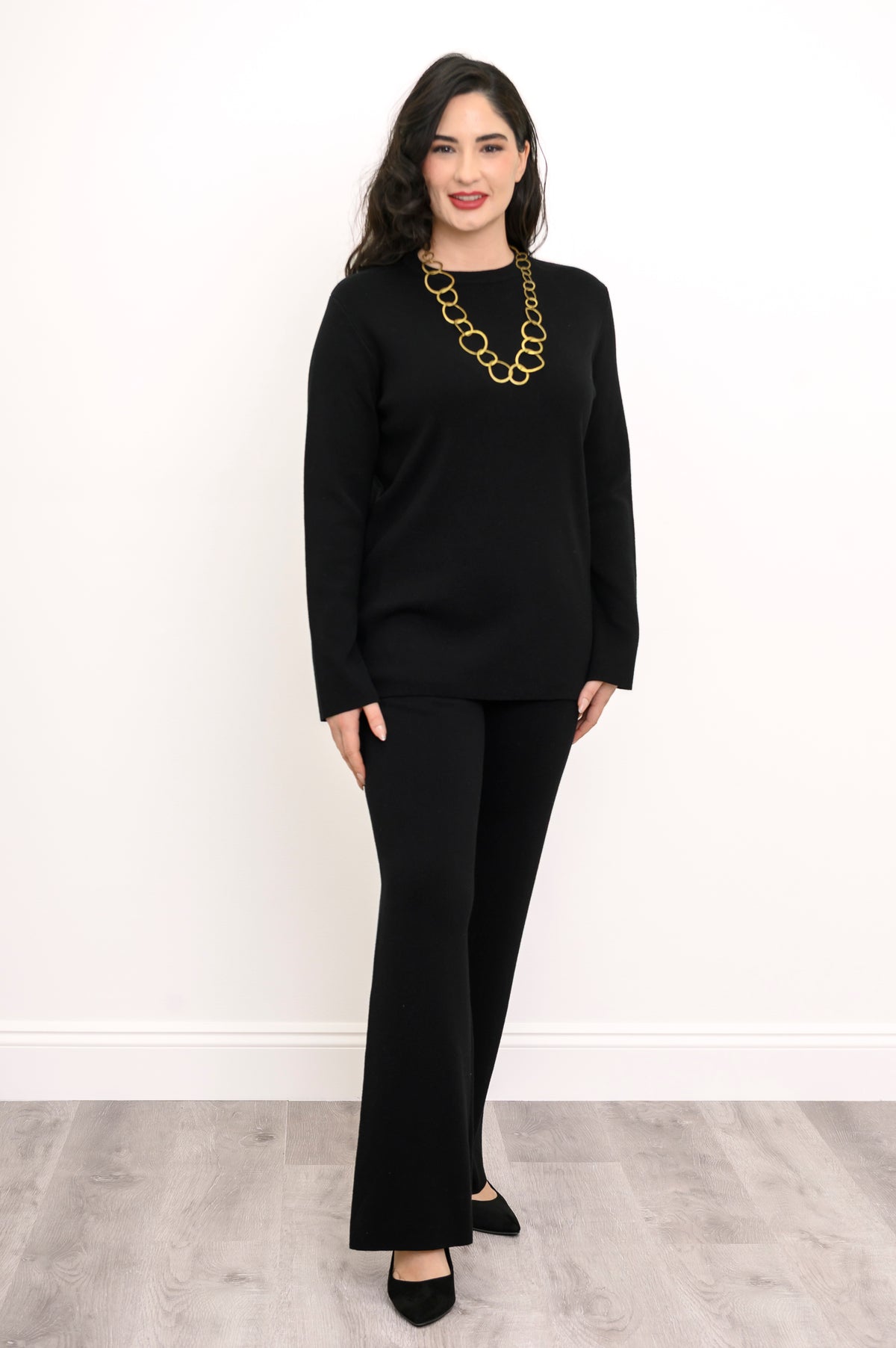 Angled view of an ebony long-sleeve knit top on a model, showcasing a comfortable, body-skimming silhouette.