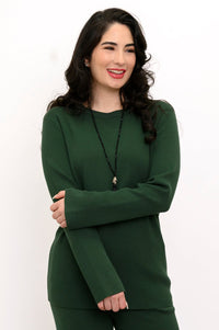 Smiling woman wearing an emerald green crew neck cotton sweater featuring a relaxed rectangular knit drape.