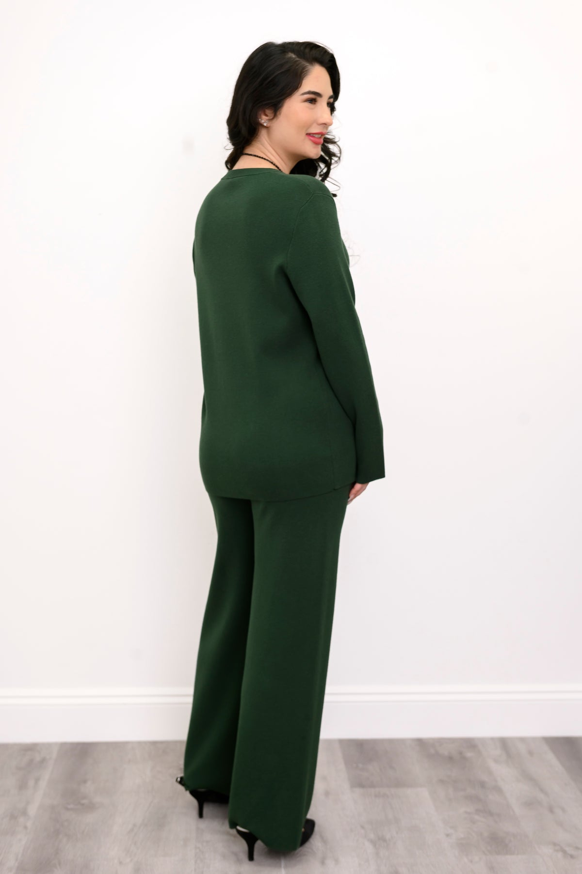 Rear view of a forest-green knit tunic on a model, highlighting its comfortable, seat-covering length.