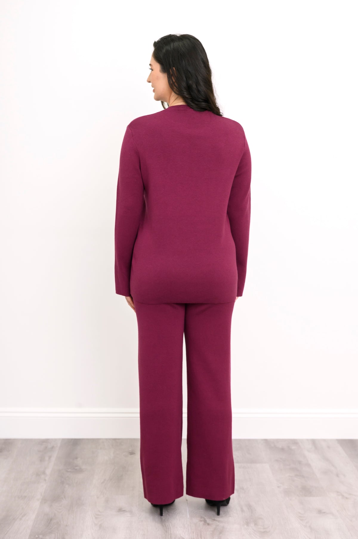 Rear view of a model in a maroon knit pullover, illustrating the clean flat finish at the cuffs and straight hem.