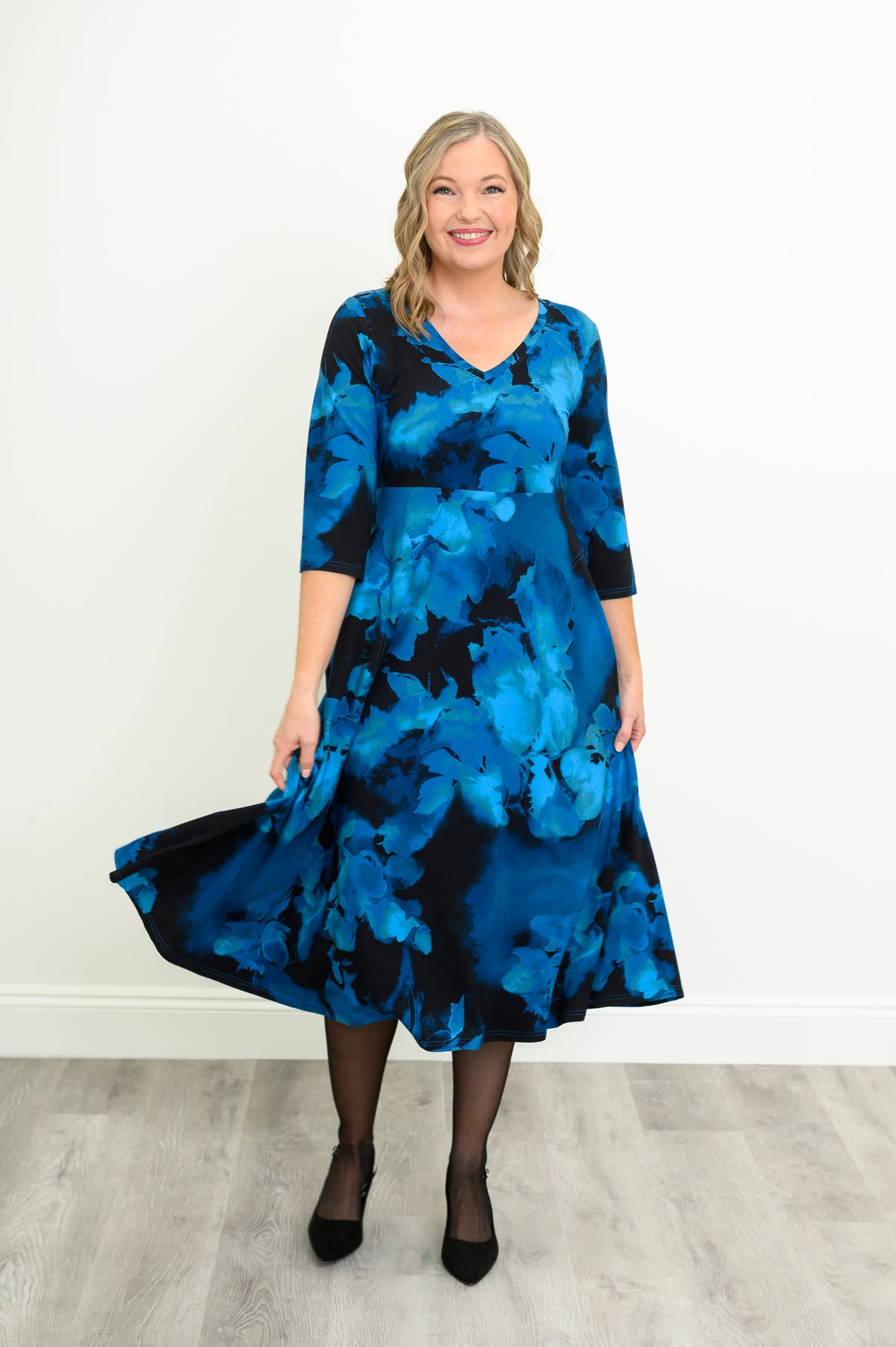 Front view of a woman modeling a blue patterned bamboo cotton midi dress styled with simple black heels.