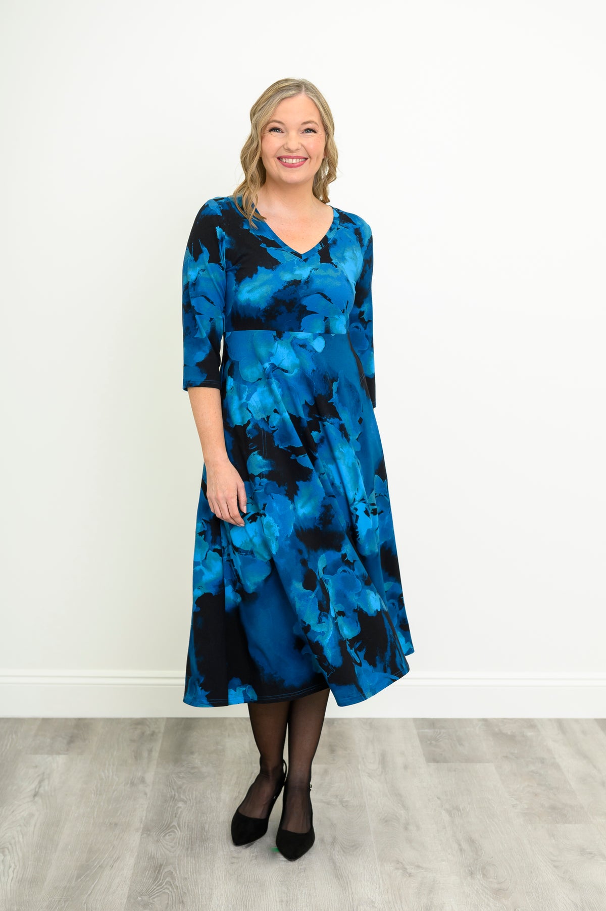 Centered front shot of an indigo floral V-neck dress featuring a structured, high-placed empire waist.