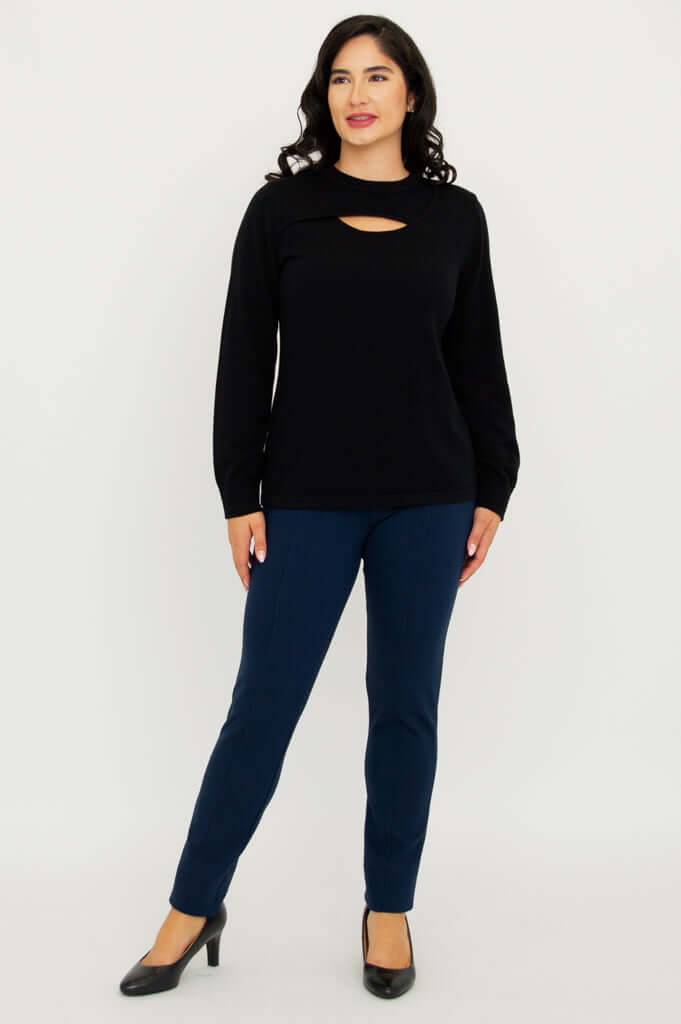 Front standing view of model in black cutout neck sweater and navy pants