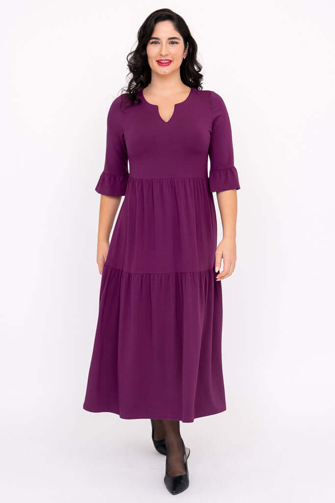 Woman in purple Bernadette midi dress standing and smiling, showing tiered silhouette