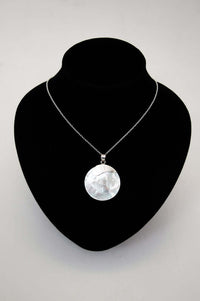 925 sterling silver necklace with round shell pendant displayed on a black bust stand