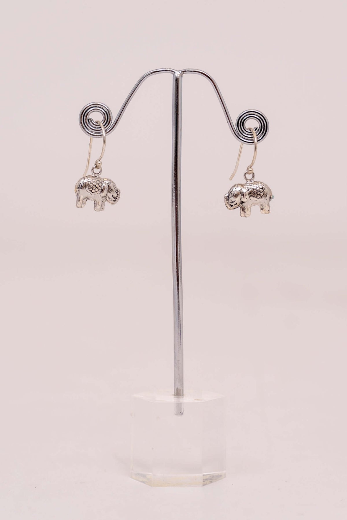 Pair of 925 sterling silver drop earrings with small elephant charms displayed on a stand
