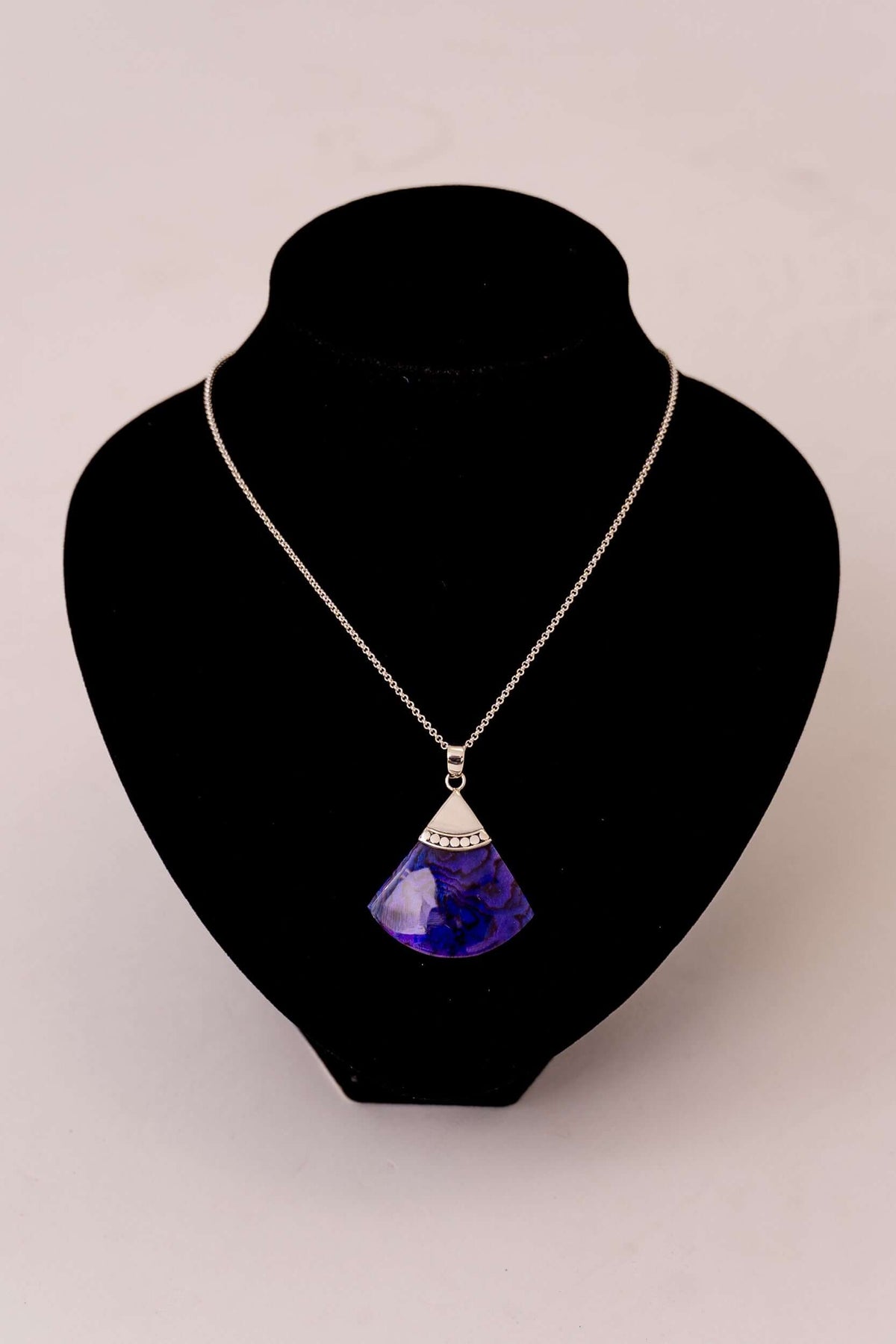 Sterling silver necklace with blue fan-shaped pendant displayed on black bust