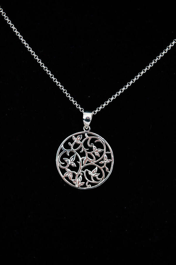 Sterling silver necklace with circular filigree vine pendant on black background