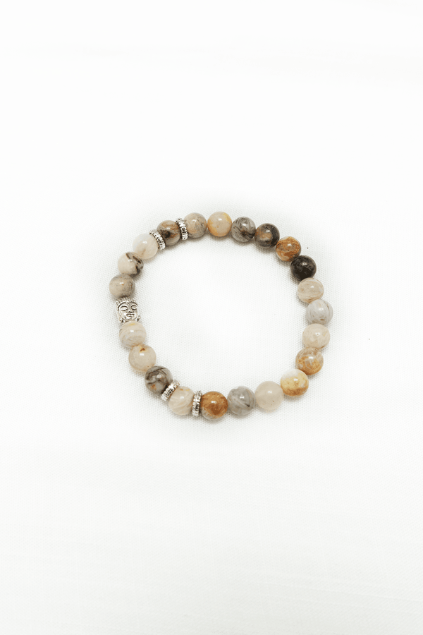 A round beaded bracelet with natural stone beads and decorative silver accents on a white background