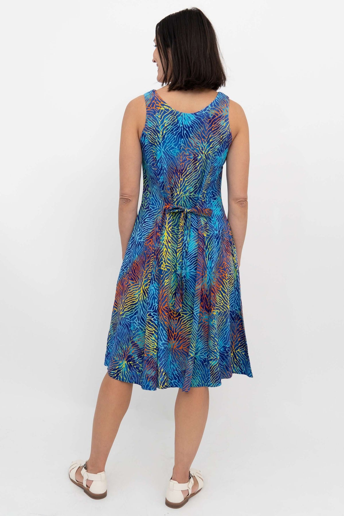 Back view of a woman in a sleeveless dress with electric palm print and tie belt