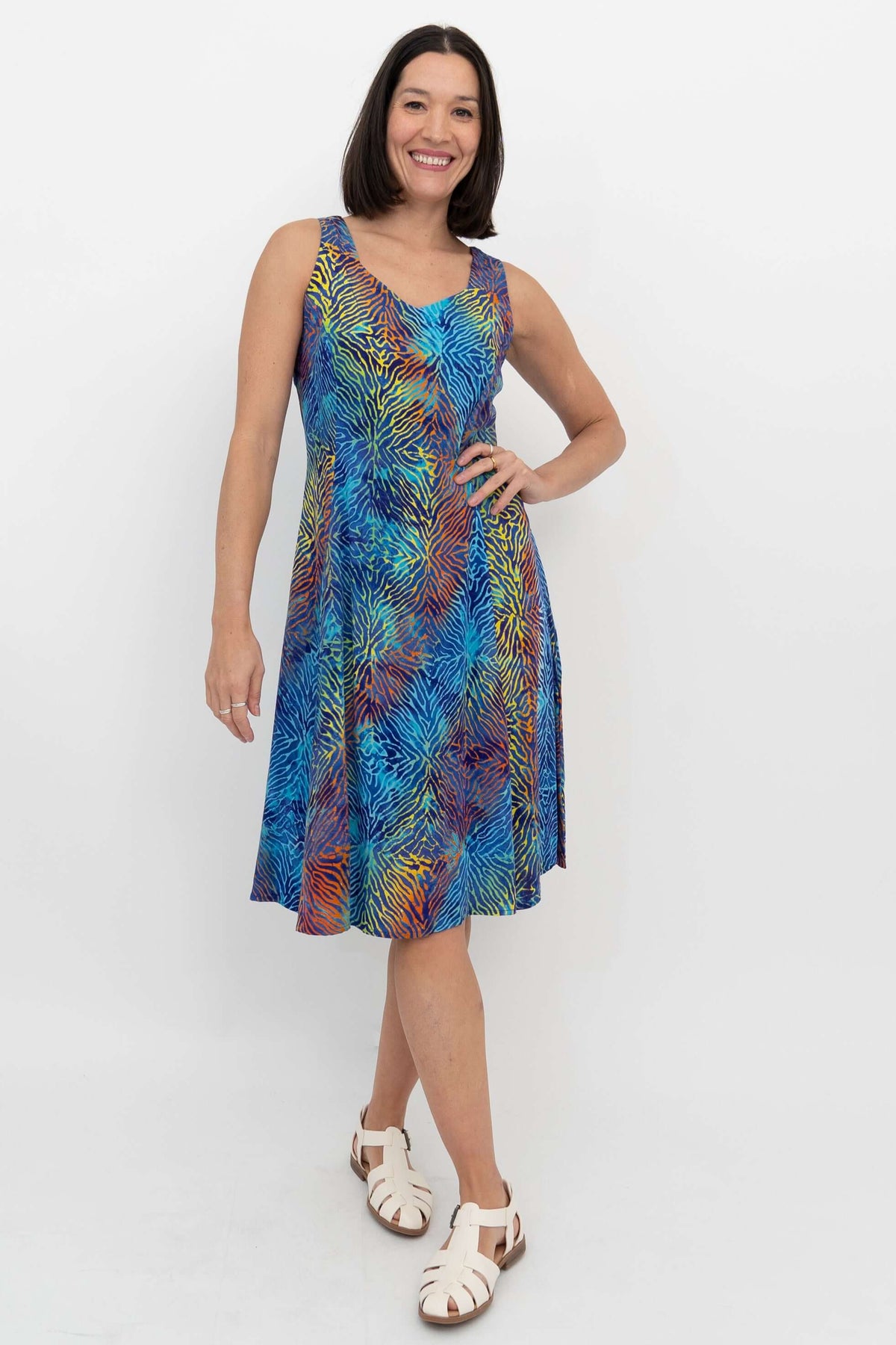 Woman wearing a sleeveless A-line dress with vibrant electric palm print, front view