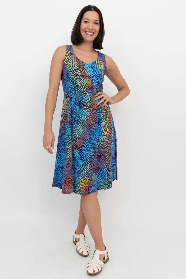 Woman wearing a sleeveless A-line dress with vibrant electric palm print, front view