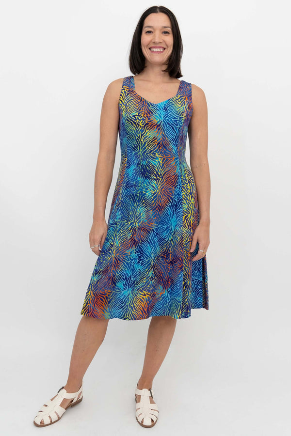 Front view of a woman in a colorful electric palm patterned sleeveless dress