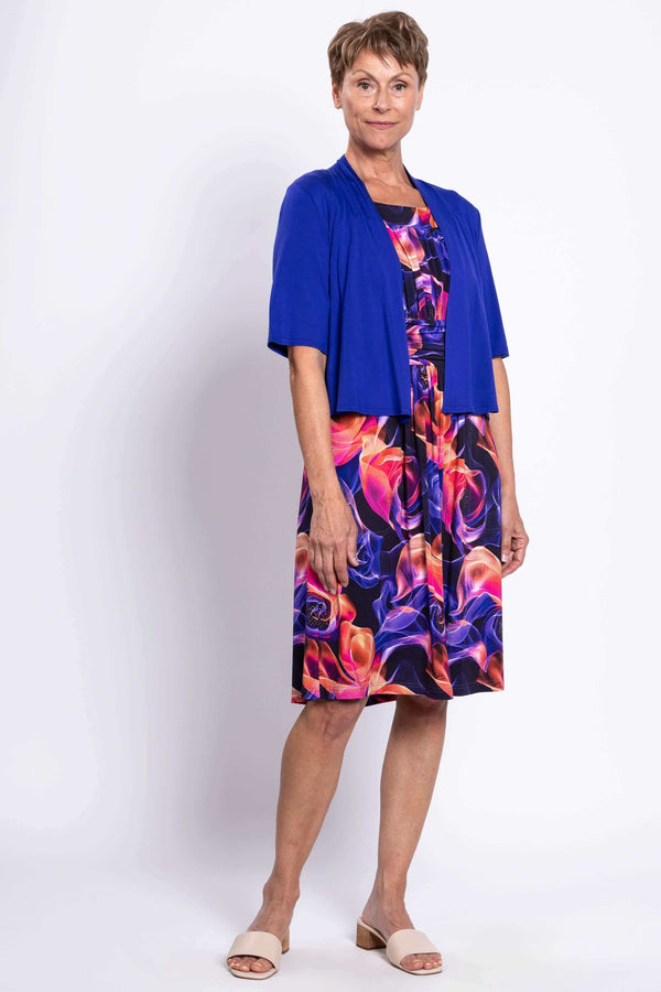 Woman wearing the swirl print dress with a royal blue open-front cardigan