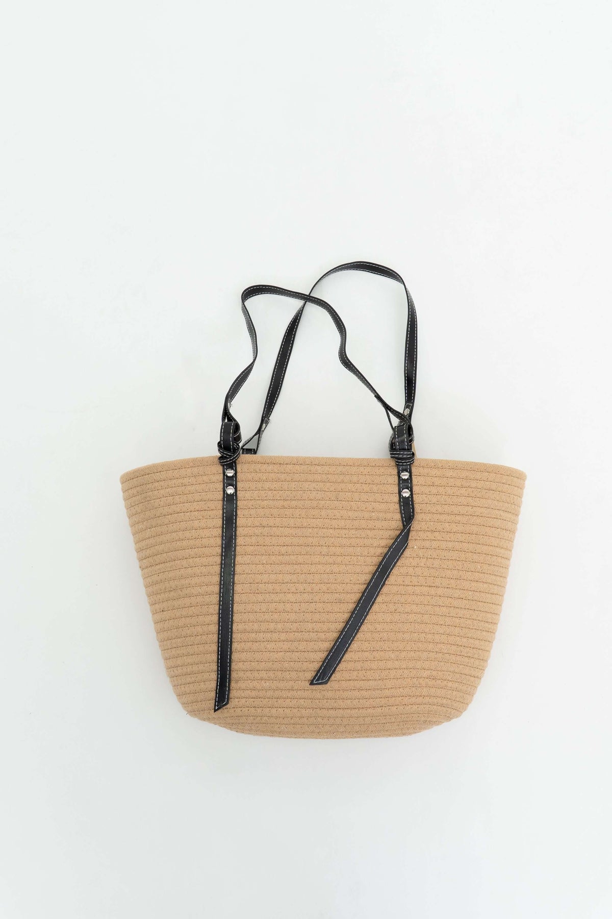 Tan cotton tote bag with black straps displayed on a white background