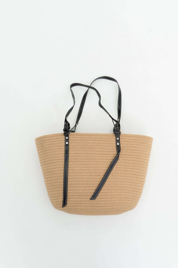 Tan cotton tote bag with black straps displayed on a white background