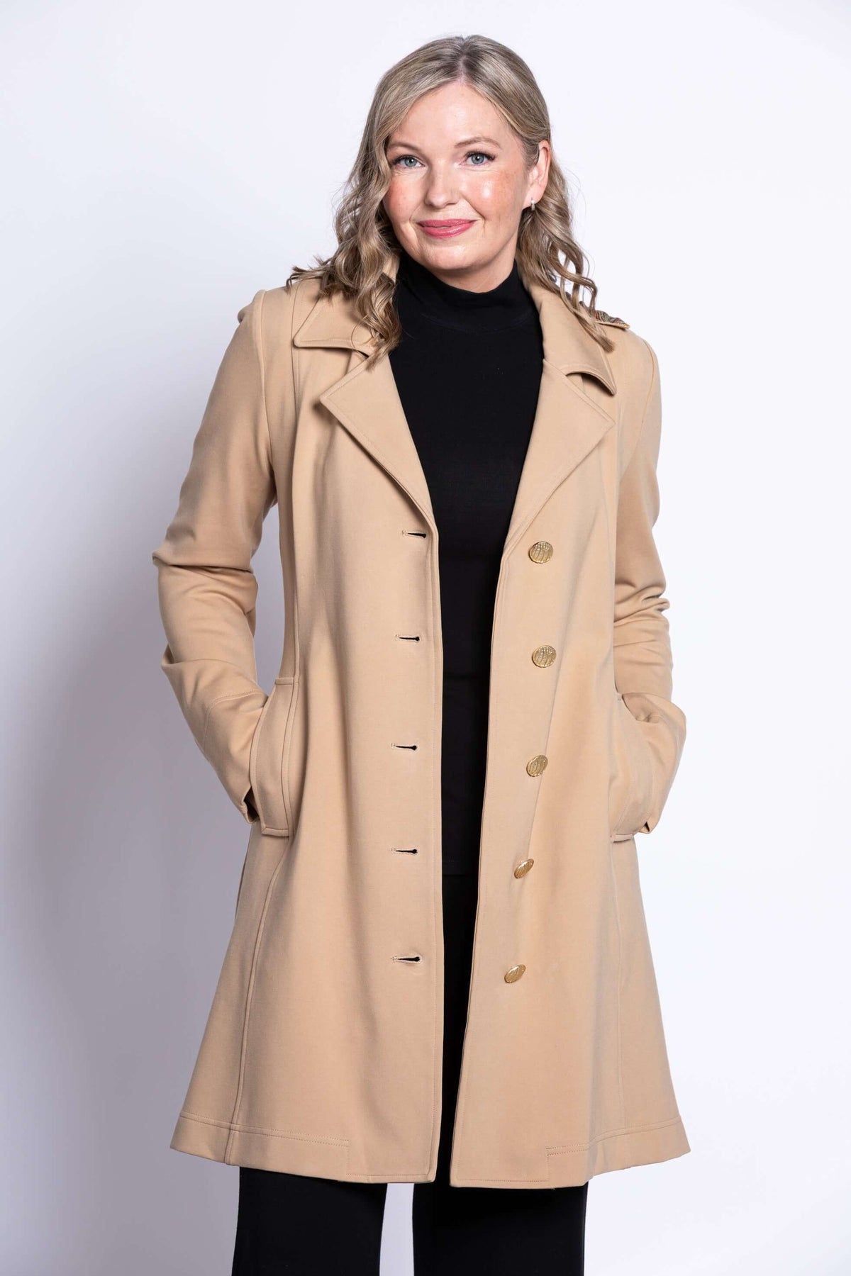 Woman wearing a tan modal trench jacket with button closure and notched collar