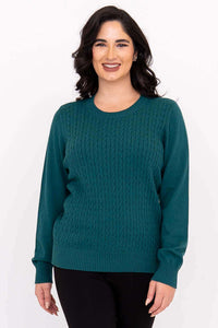 Woman wearing a teal cable knit crew neck sweater with ribbed cuffs