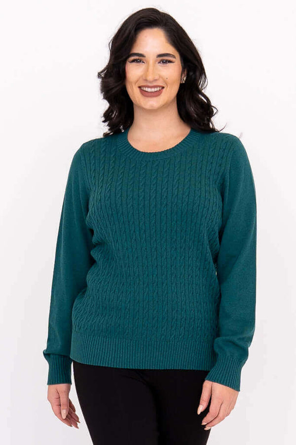 Woman wearing a teal cable knit crew neck sweater with ribbed cuffs