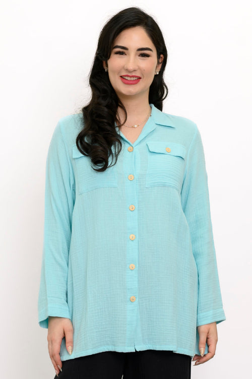 Woman wearing a light blue button-up shirt and black pants against a white background, front view