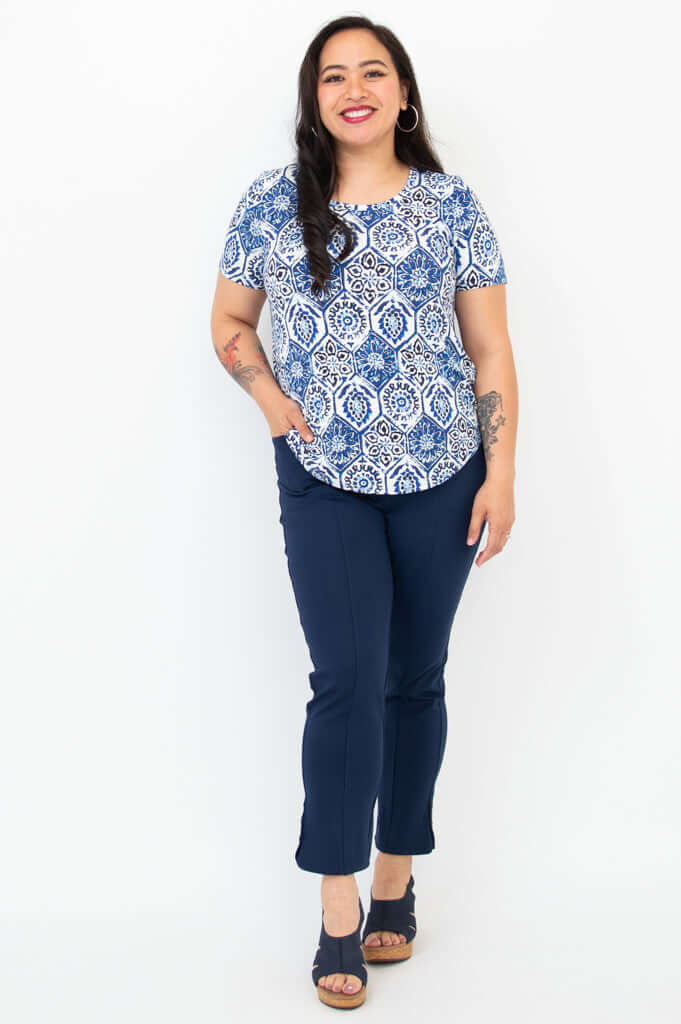 Woman smiling in Tessa Tee blue mosaic top and navy pants, hands in pockets