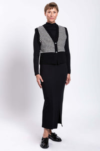 Three-quarter front view of model wearing black and white striped vest and black skirt