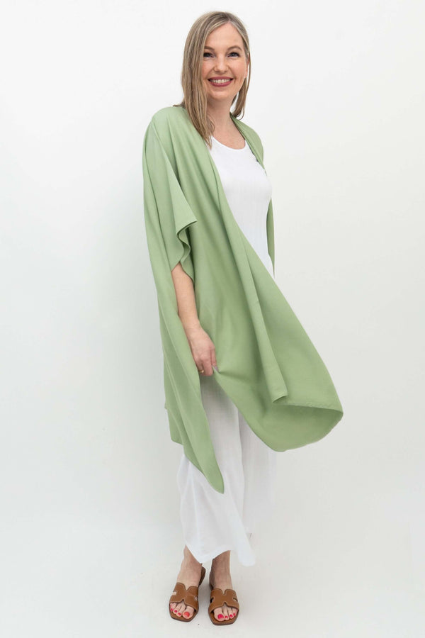 Three-quarter front view of woman modeling sage green kimono wrap in motion