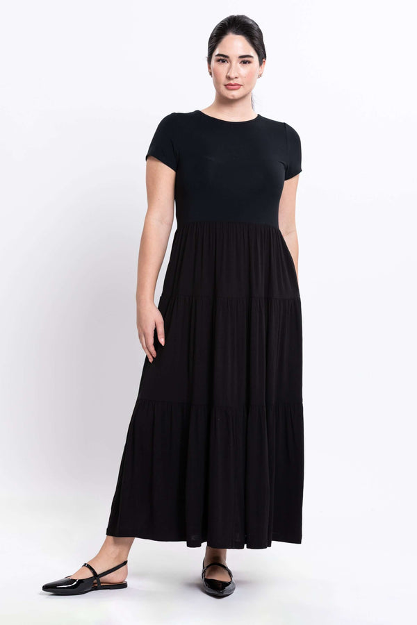 Three-quarter front view of woman in black tiered maxi dress