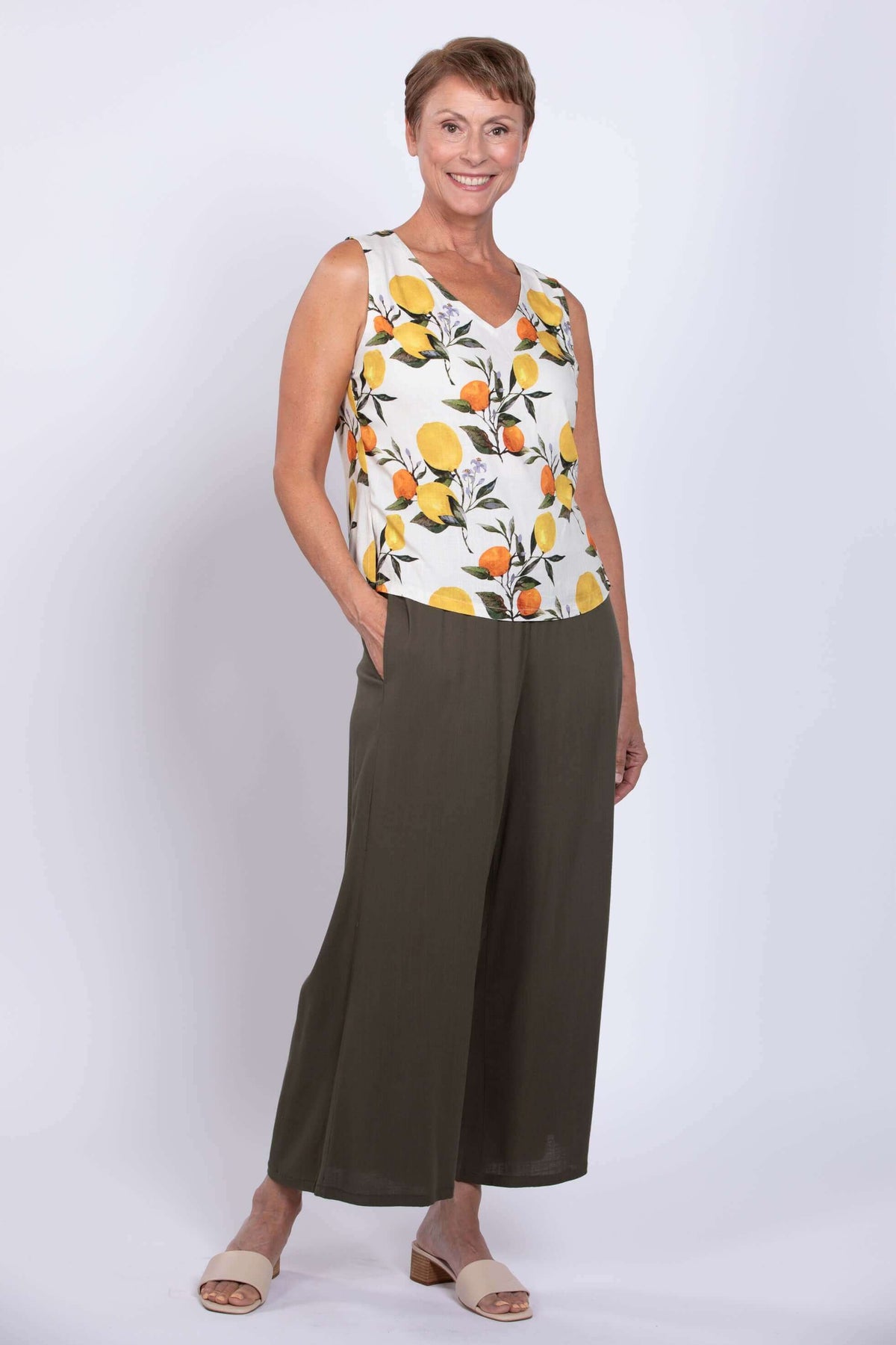 Three-quarter pose of woman in sleeveless lemon print tank top with pockets