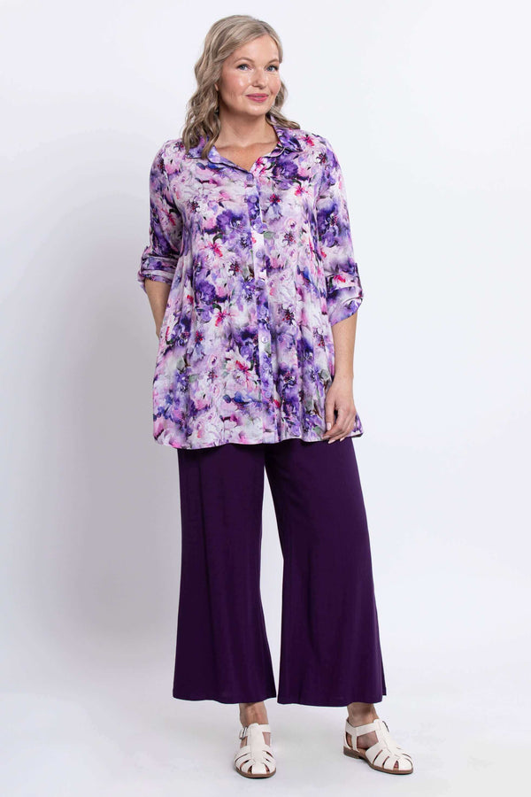 Three-quarter view of model in a purple floral oversized tunic and dark purple pants