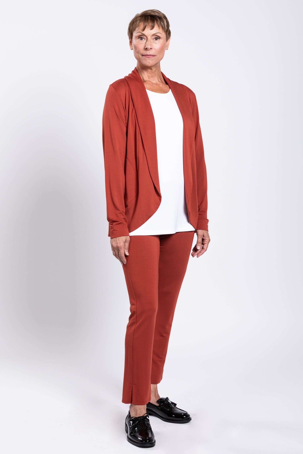 Three-quarter view of woman modeling rust French Terry open front jacket and matching pants