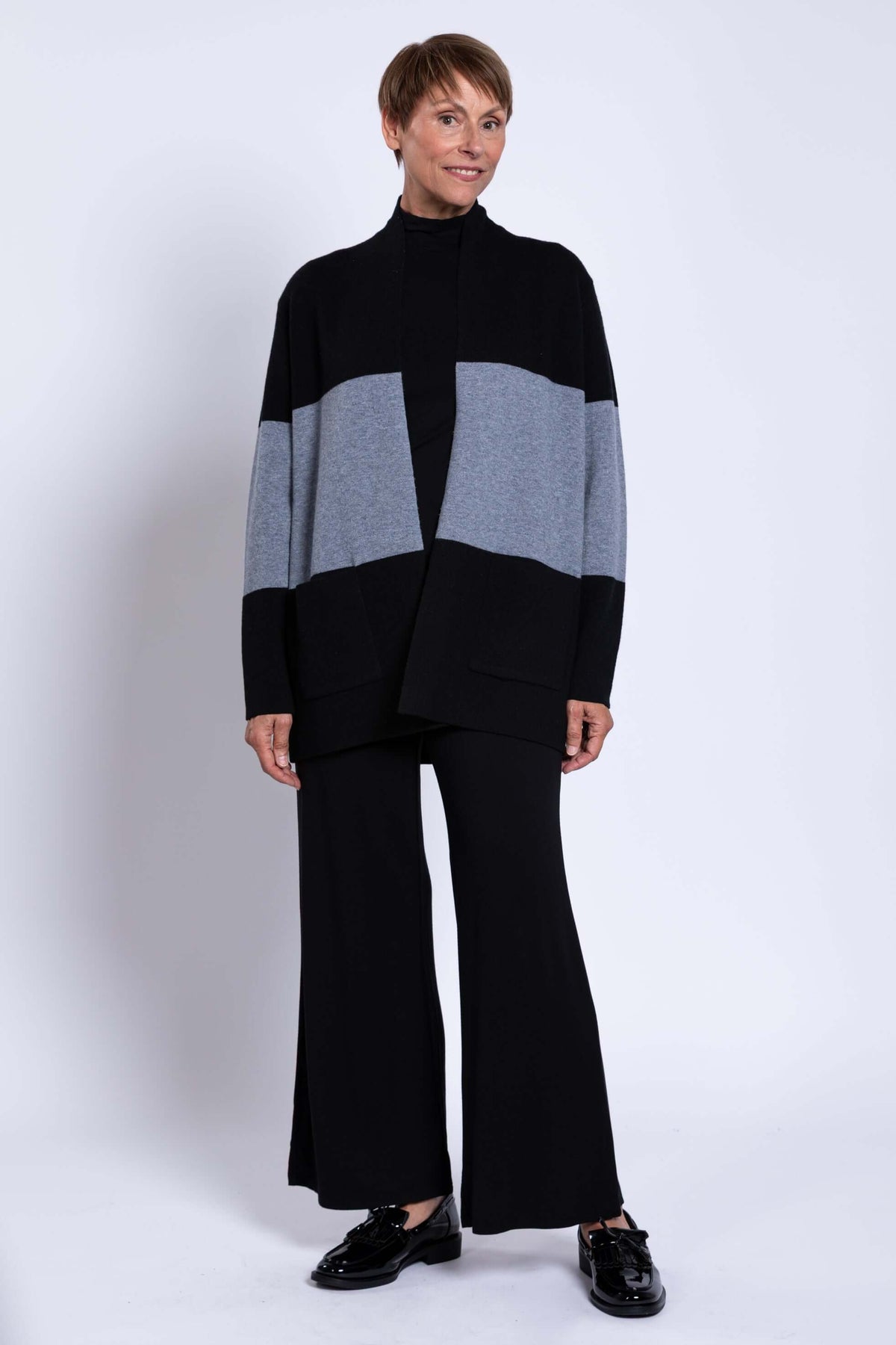 Three-quarter view of woman modeling black and grey colour-block open front sweater