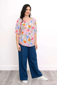Three quarter front view of model in Liza floral blouse styled with blue pants