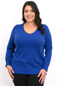 Close up front view of a woman wearing an absolute blue v-neck knit sweater over black pants.