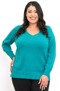 Close up front view of a woman wearing a bright turquoise v-neck knit sweater over black pants.