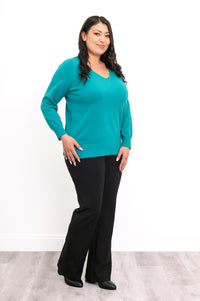 Three-quarter view of a woman modeling a breathable teal cotton v-neck sweater with side hem vents.