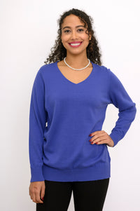 Front view of a woman in a comfortable violet blue long sleeve sweater providing low-hip coverage.