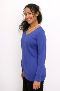 Three-quarter view of a woman wearing a breathable violet cotton v-neck sweater with side hem vents.