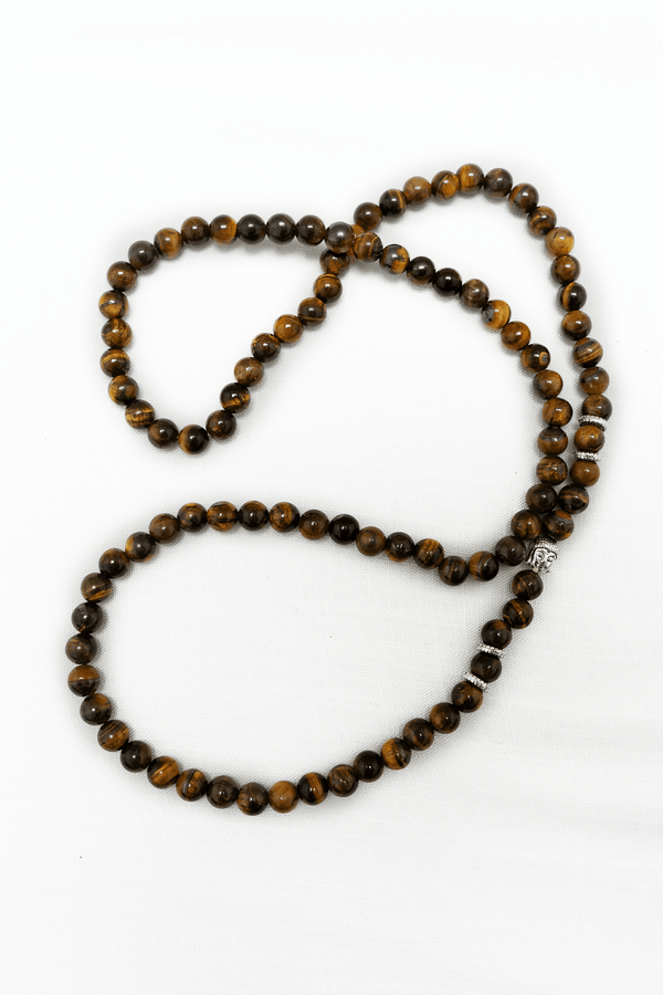 Tiger Eye bead mala necklace with silver accents laid out on a white background